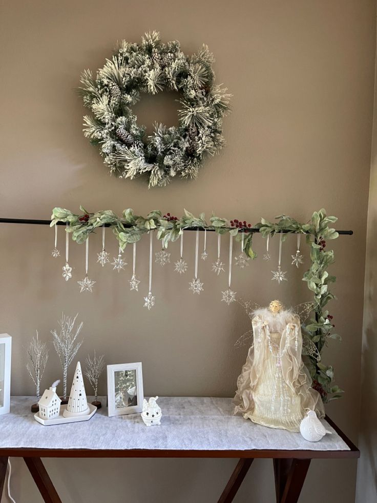 a table topped with pictures and wreaths next to a wall mounted snowflake