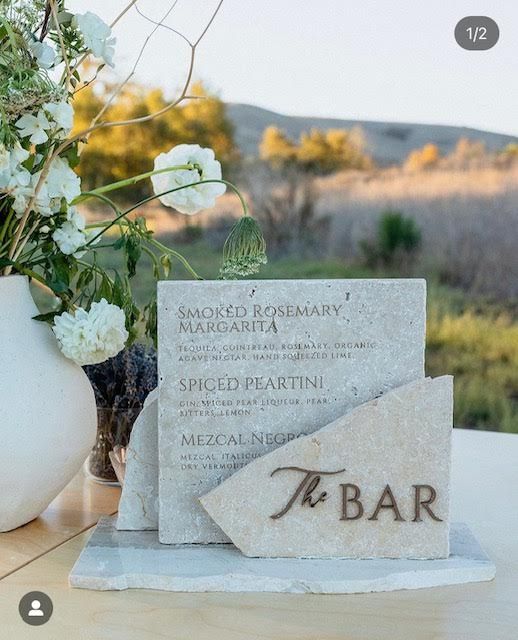 a table topped with a vase filled with white flowers and a sign that says bar