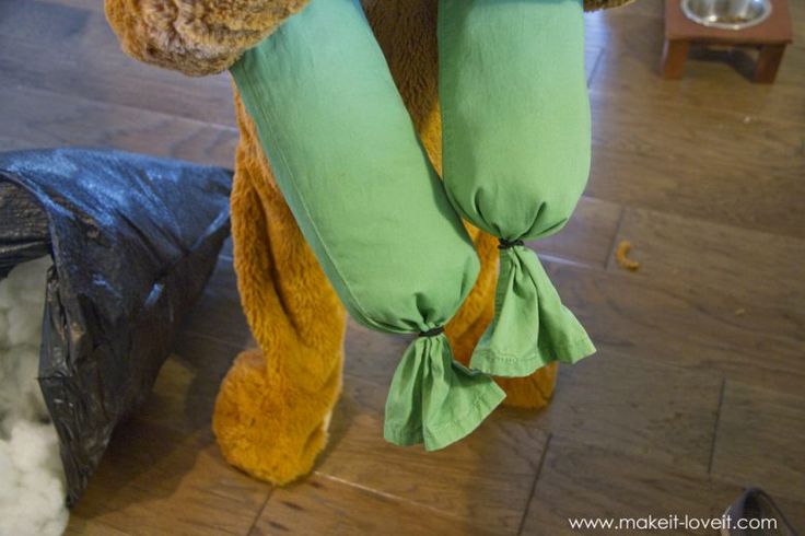 a stuffed animal hanging from the side of a wooden floor next to a trash can