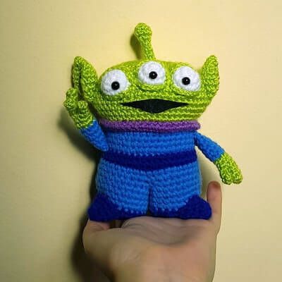 a hand holding a crocheted toy with eyes