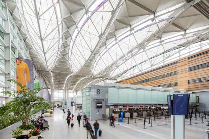 people are walking through an airport terminal with many tables and chairs on the sides of it