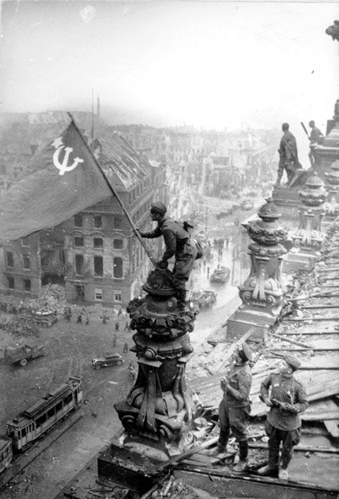 an old black and white photo shows men working on a building with a red flag