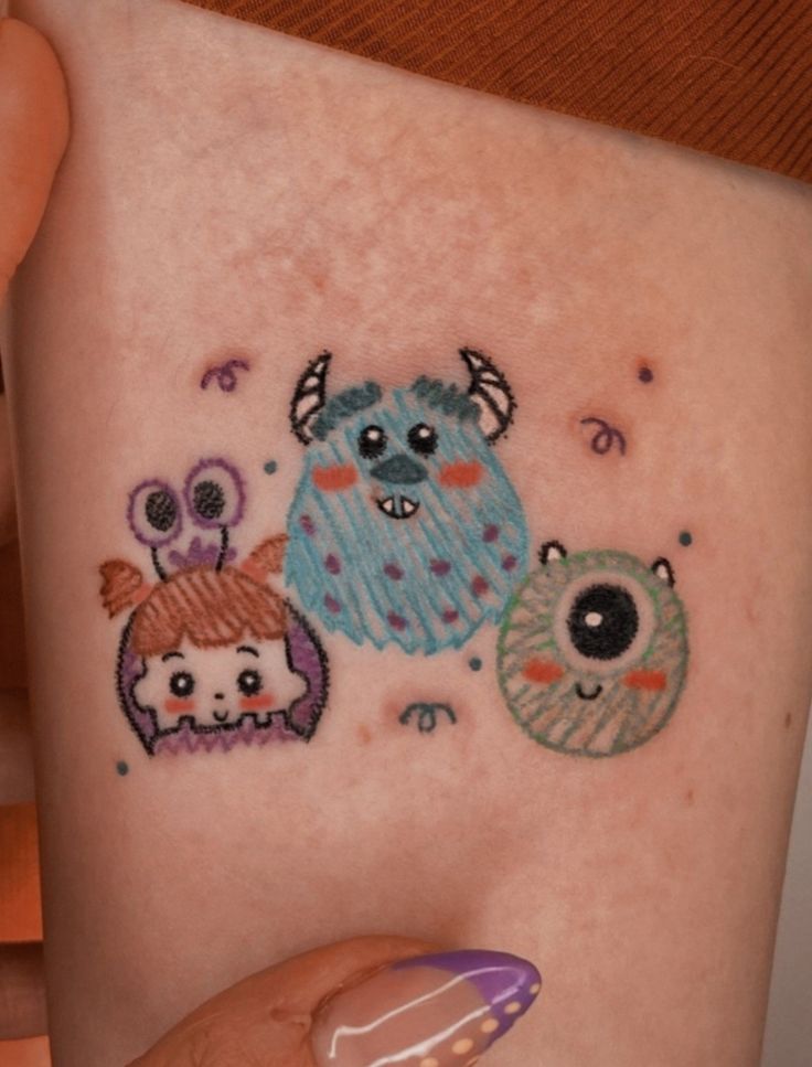 a woman's arm with tattoos on it and three small monsters in the middle