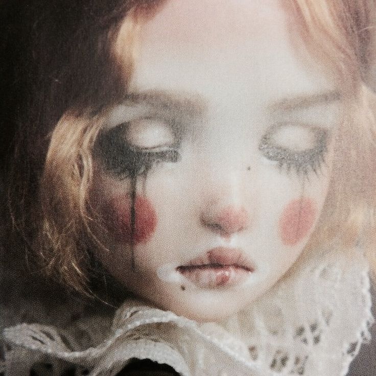 a close up of a doll's face with blood on her cheek and eyes