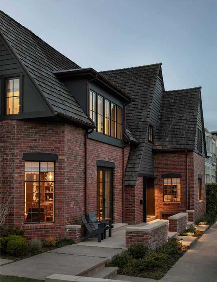 a row of brick houses with windows and lights on the side of each building at dusk