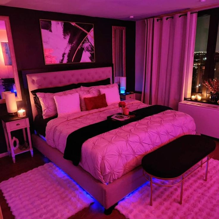 a large bed sitting in a bedroom next to a window with purple lights on it