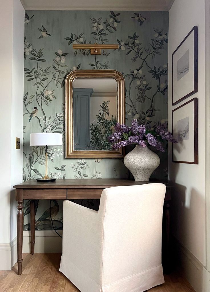 a white chair sitting in front of a mirror on top of a wooden table next to a vase filled with flowers