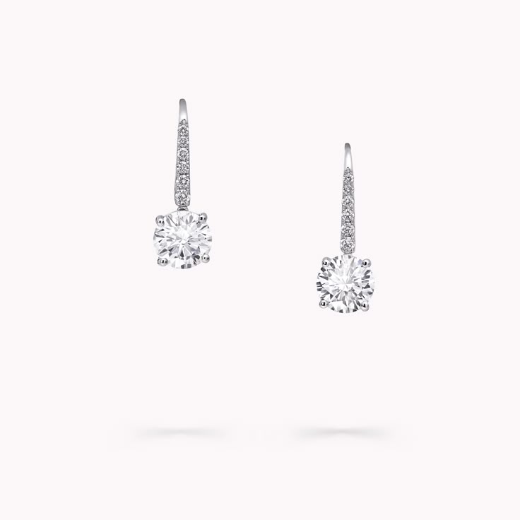 Elegantly set upon pavé diamond swan hooks, the unrivalled brilliance of a round diamond is celebrated with our round diamond earrings. The essence of timeless classicism, the simple setting of the stones, with minimal metal on display, amplifies and enhances their scintillating beauty. The Classic Graff collection celebrates the purity and fire of the finest Graff diamonds showcased in eternally elegant silhouettes. Model wears an elegant pair of Classic Graff round diamond earrings with a tota Graff Earrings, Graff Jewelry, Earrings Platinum, Graff Diamonds, Round Diamond Pendant, Round Diamond Earrings, Diamond Earrings Studs Round, Bridal Jewelry Collection, Fine Diamond Jewelry