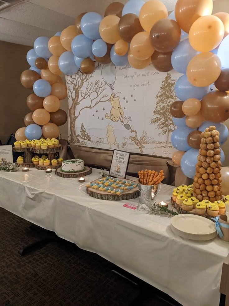 a table with desserts and balloons in the shape of winnie the pooh on it