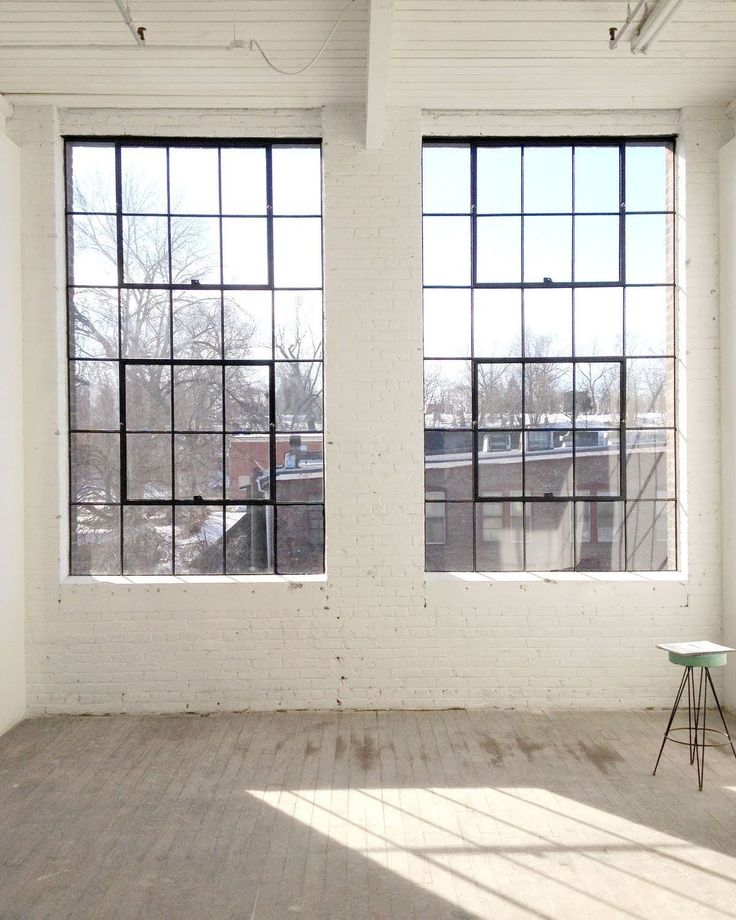 an empty room with two large windows and a small table