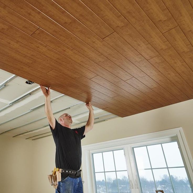 a man is working on the ceiling in his new home with wood planks installed