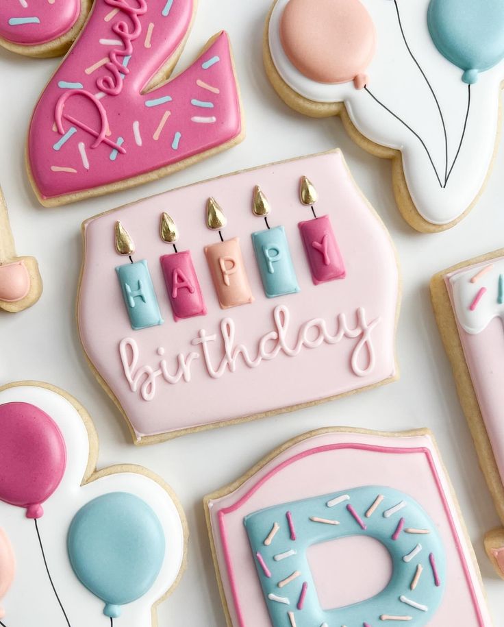 decorated birthday cookies with candles and balloons on a white table top, including one for the first year