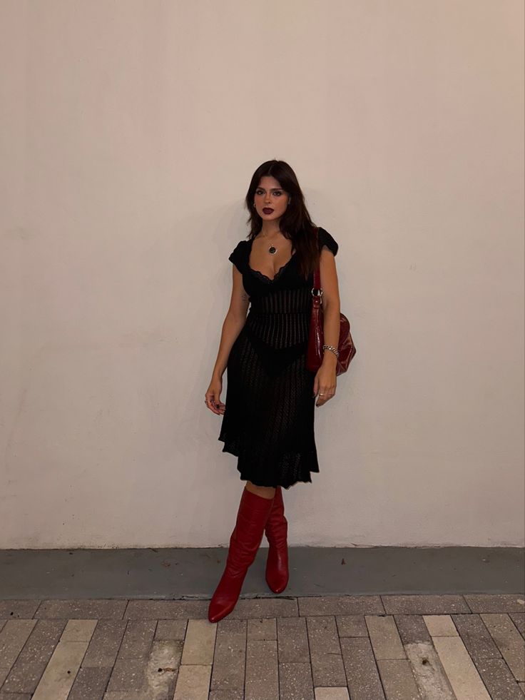 Red boots styled with a black crochet dress and red slouchy bag Red Calf Boots Outfit, Winter Heels Outfit Dress, Black Mini Skirt Black Boots, Crochet Dress With Boots, Fall Skirt And Dress Outfits, Dress With Patterned Tights, Black Dress Red Cowgirl Boots, Red Boots Aesthetic Outfit, Black Skirt And Black Boots Outfit