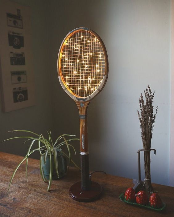 a lighted tennis racquet sitting on top of a wooden table next to a potted plant