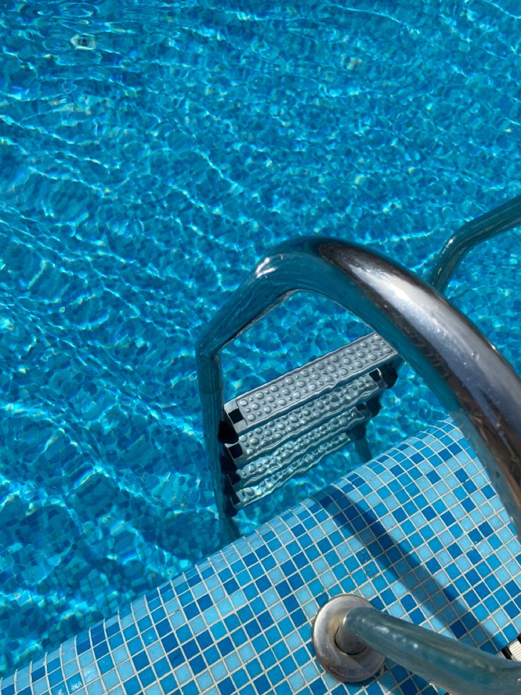 an empty swimming pool with blue tiles and water