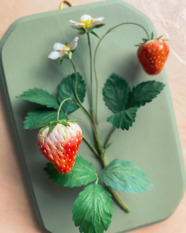 two strawberries on a green tray with white flowers