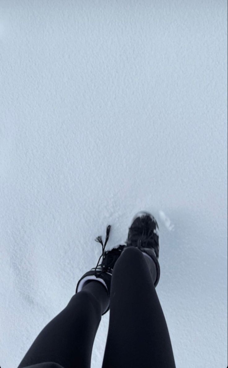 someone is standing in the snow with their feet up