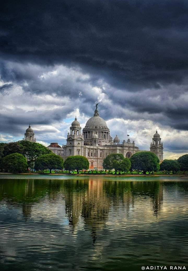 a large building sitting on top of a lush green field next to a body of water