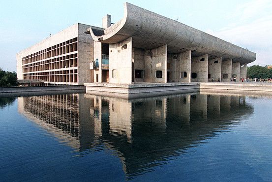 a large building sitting on top of a lake next to a tall building with columns