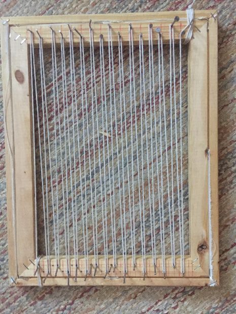 an old weaving loom is sitting on the floor next to a carpeted wall