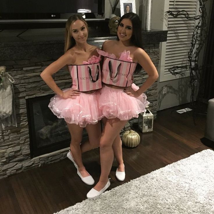 two women in pink dresses standing next to each other on a wooden floor near a fireplace