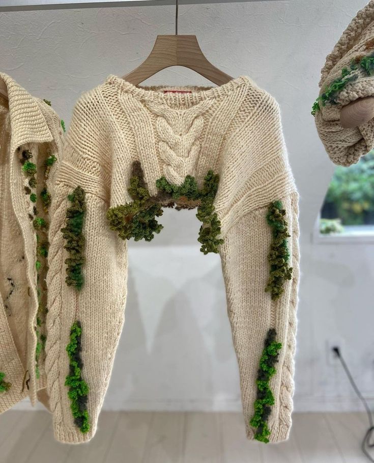 two sweaters with ivy growing on them hanging from hooks