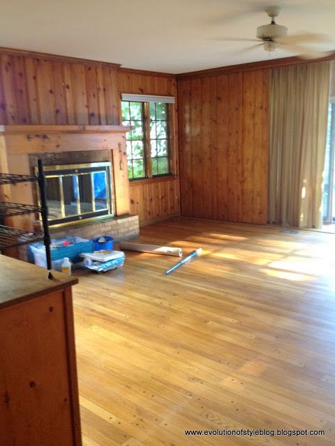 an empty living room with wood paneling on the walls and hard wood flooring