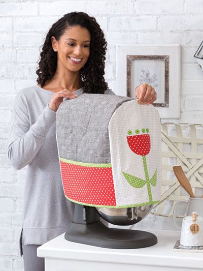 a woman holding up a flower pot holder