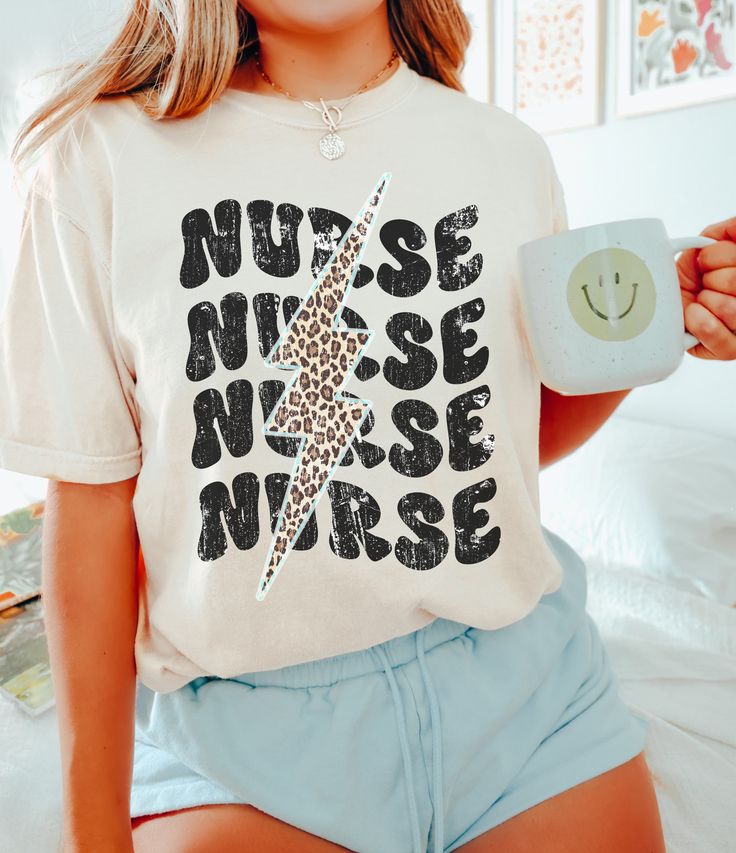 a woman holding a cup and smiling while wearing a t - shirt that says nurse nurse