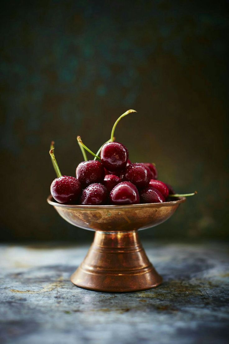 a bowl filled with cherries sitting on top of a table