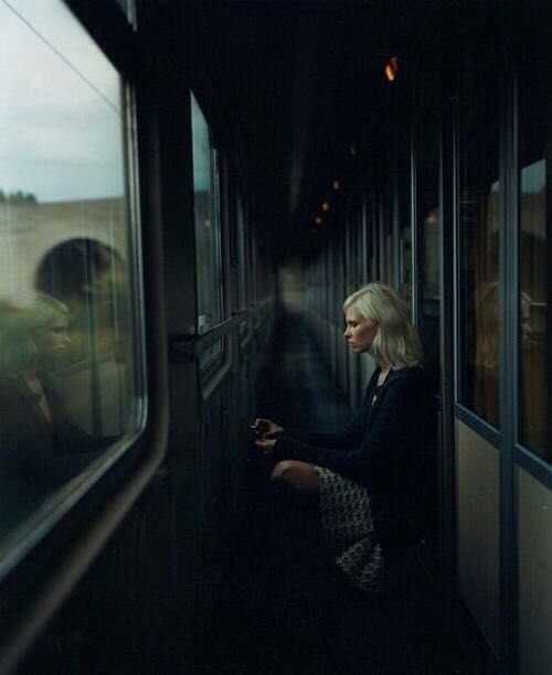 a woman sitting on a train looking out the window at another person standing next to her