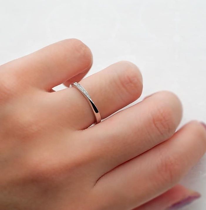 a woman's hand with a diamond ring on top of her finger, against a white background