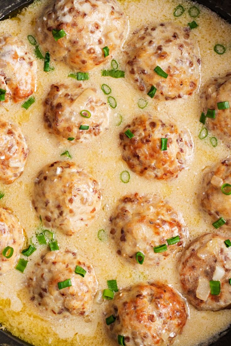 a skillet filled with meatballs covered in gravy and topped with green onions