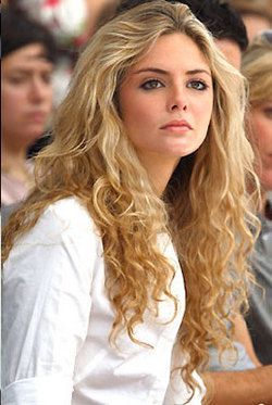 a woman with long blonde hair sitting in front of a crowd