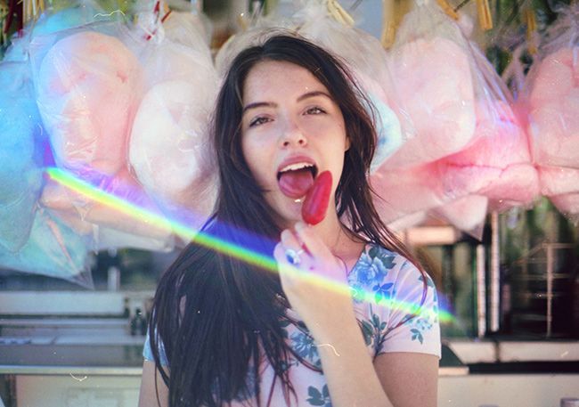 a woman sticking her tongue out in front of some food hanging from the ceiling above her head