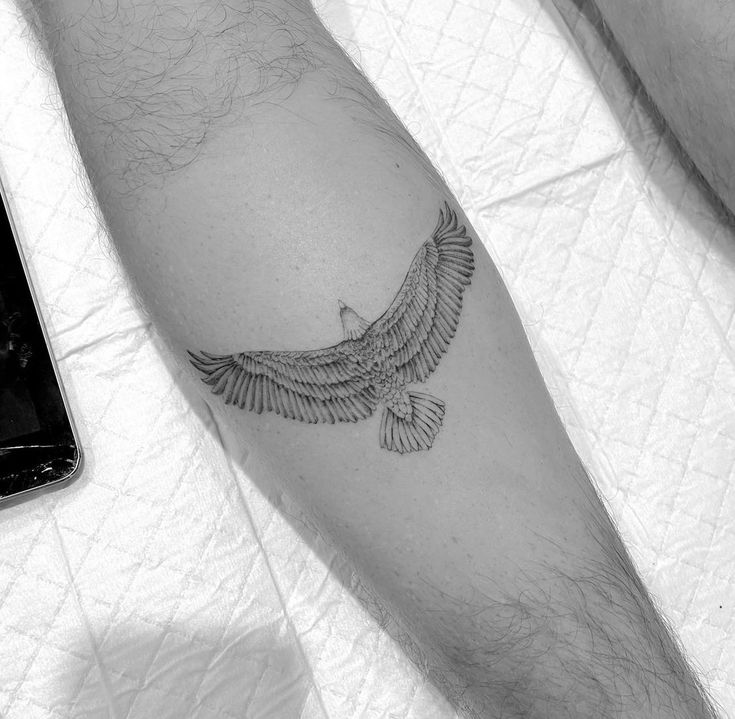 a black and white photo of a person's arm with a bird tattoo on it