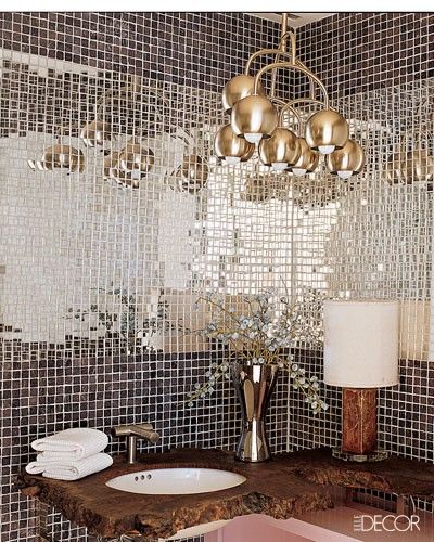 a bathroom sink sitting under a chandelier in front of a mirror covered wall