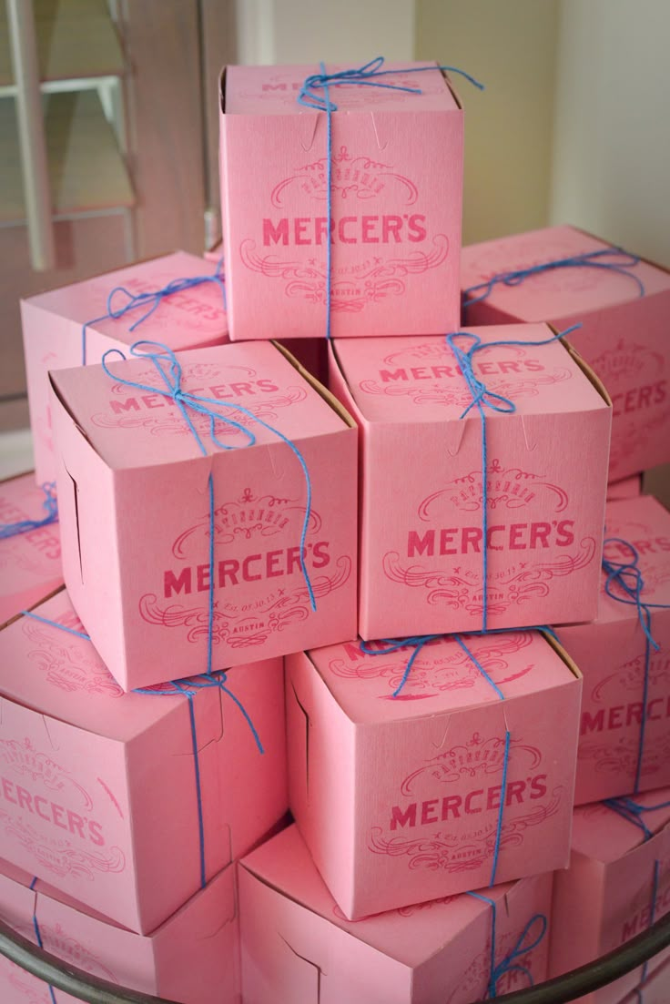 pink boxes are stacked on top of each other with blue string wrapped around the edges