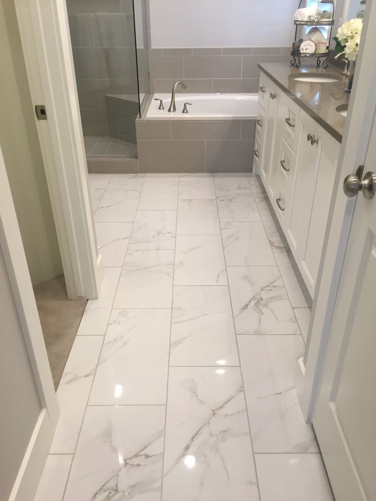 a bathroom with white marble flooring and gray walls, along with a bathtub