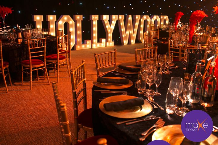 a table set up for a formal dinner with hollywood letters on the wall behind it