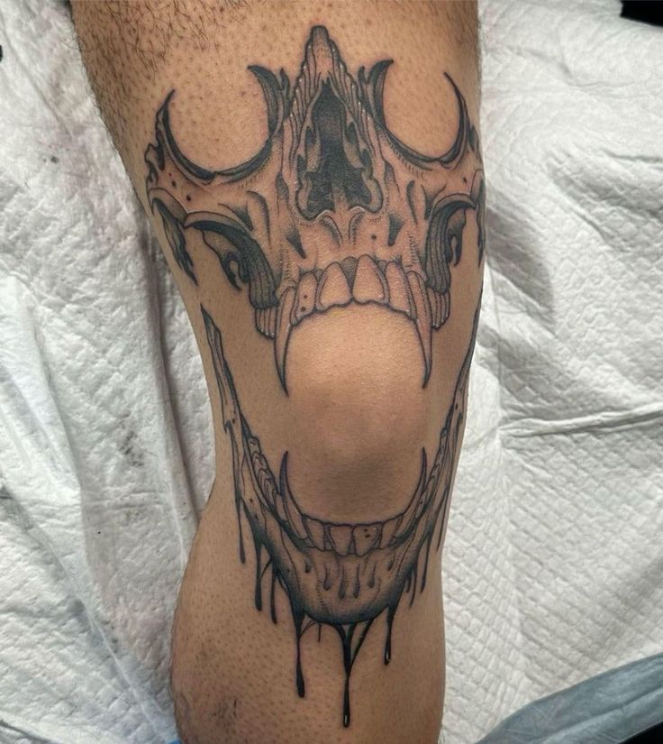 a close up of a person's leg with a tattoo on it and an evil face