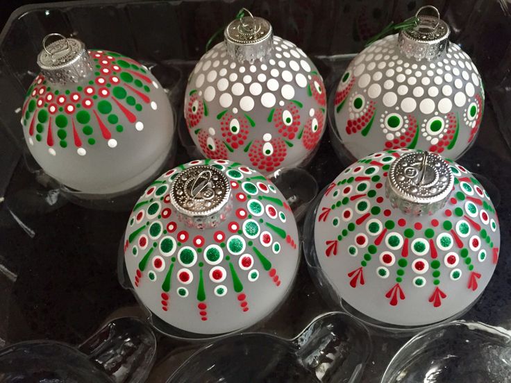 four christmas ornaments are sitting in a glass box on top of each other, all decorated with different colors and designs