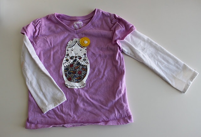 a purple and white shirt with an owl on it's chest, sitting on a table