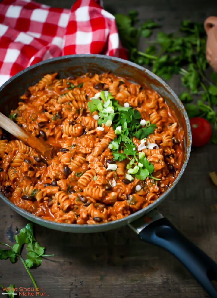 a skillet filled with pasta and garnished with parsley on the side