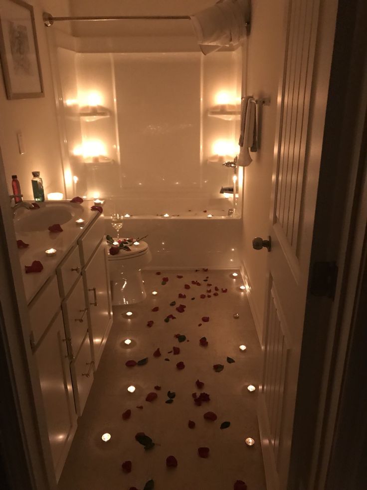 a bathroom with candles and rose petals on the floor