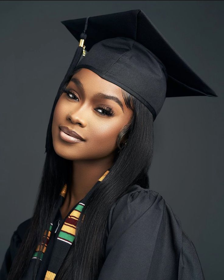 a woman wearing a graduation cap and gown with long black hair in front of a gray background