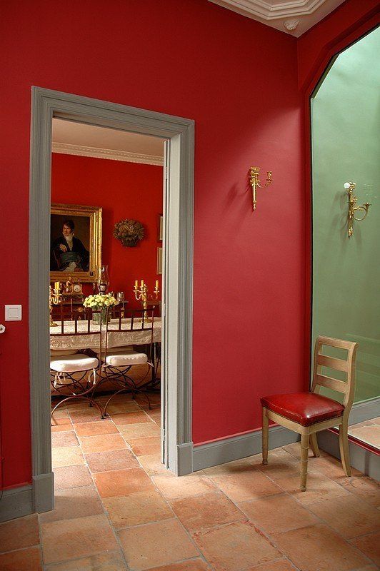 an open door leading to a dining room with red walls and tile flooring on the ground