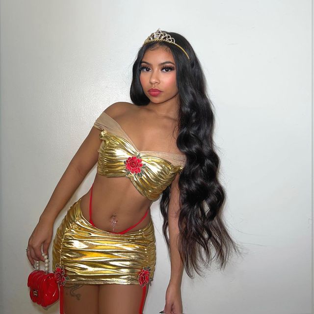 a woman with long black hair wearing a gold outfit