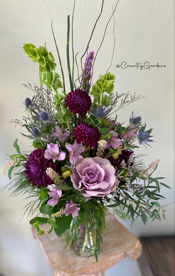 a vase filled with purple flowers and greenery