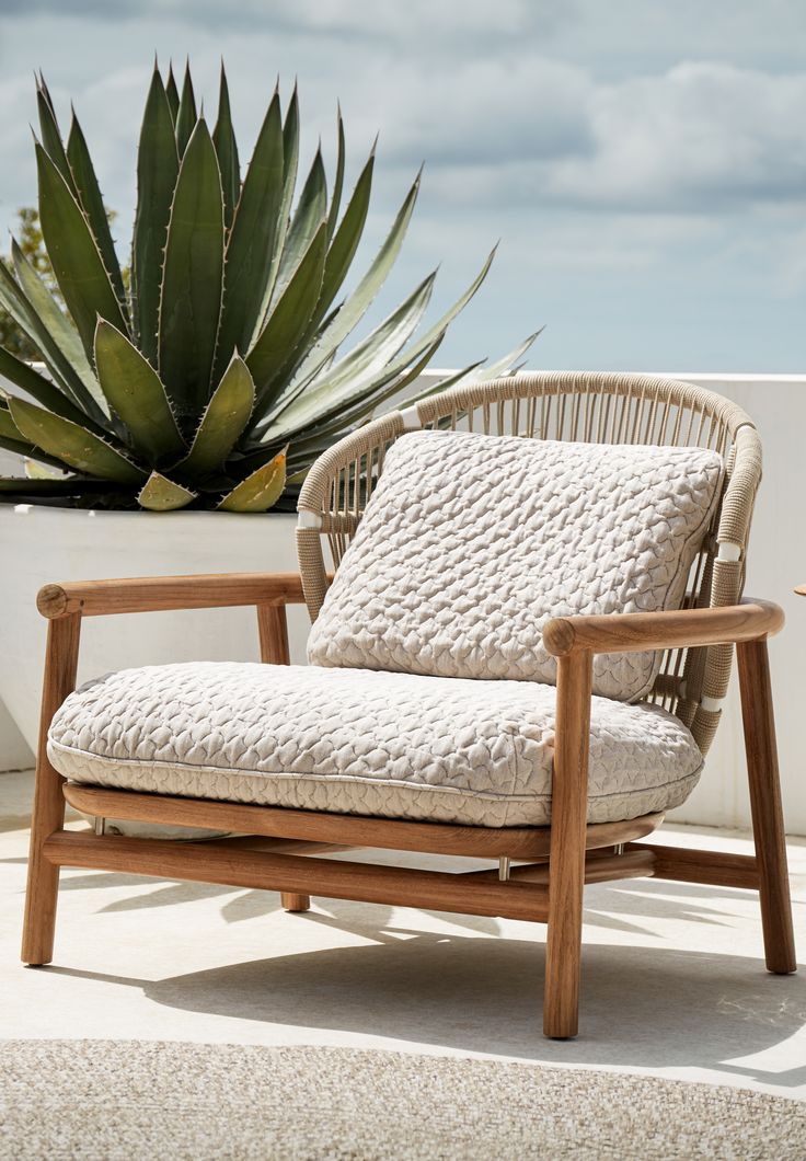 a wooden chair sitting on top of a white floor next to a potted plant